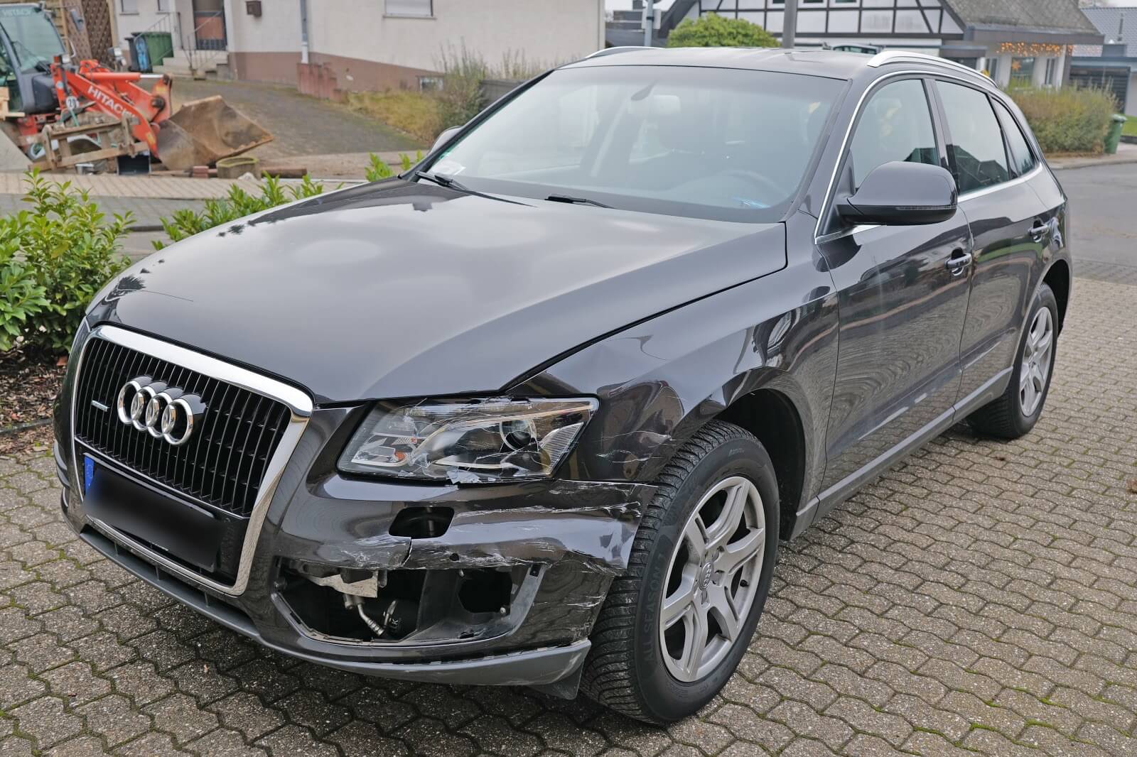 Schwarzer Audi-SUV mit Frontschaden am rechten Stoßfänger, steht auf Kopfsteinpflaster und eignet sich für ein Schadensgutachten